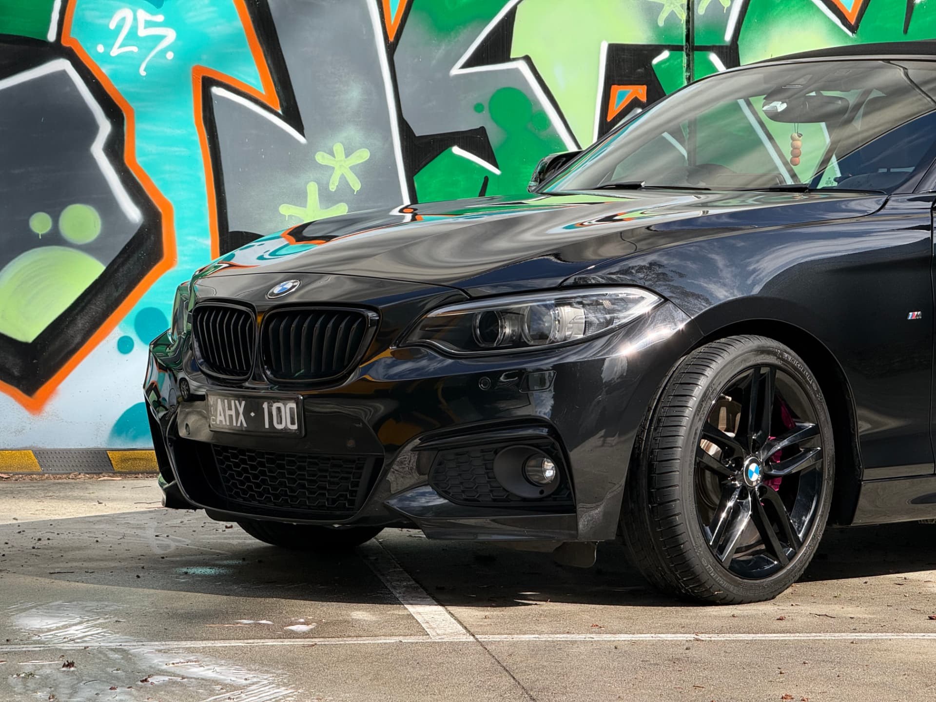 Black BMW detailed and shining in front of a graffiti wall